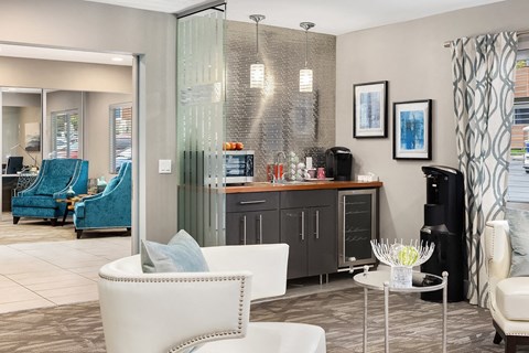 a living room with chairs and a kitchen in the background